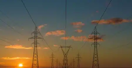 Die Sonne geht über Stromleitungen auf.