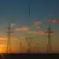Die Sonne geht über Stromleitungen auf.