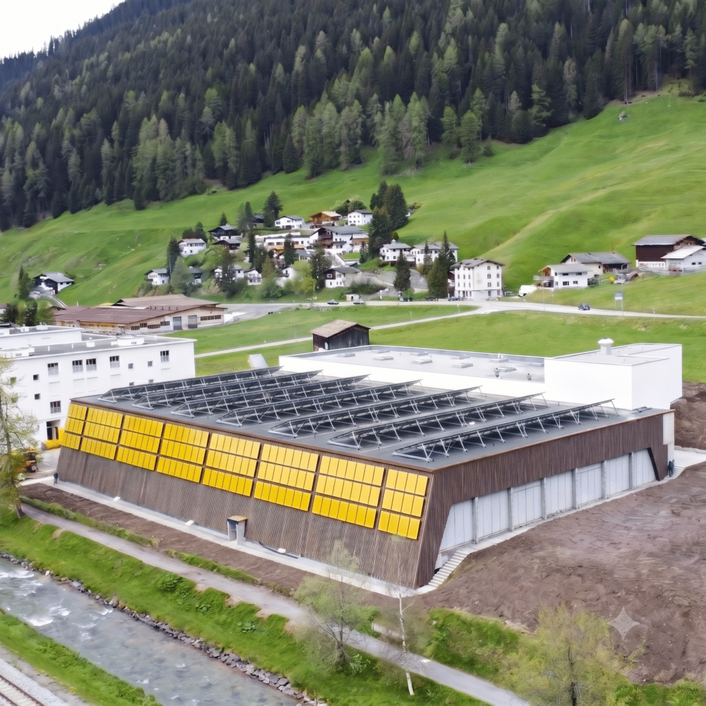 KI-generierte Visualisierung der PV- und Fassadenanlage auf Sporthalle Färbi in Davos. Die Anlage wird in den üblichen dunklen Farben gebaut.