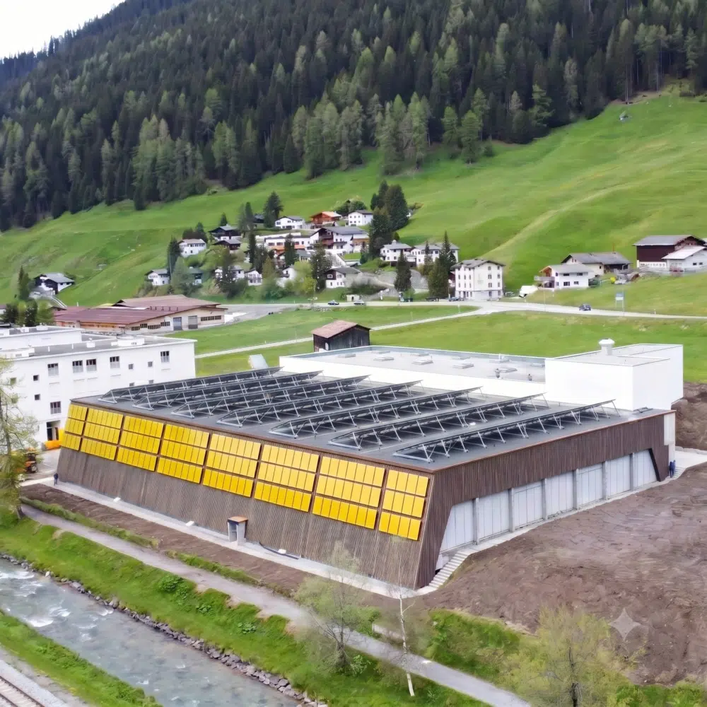 KI-generierte Visualisierung der PV- und Fassadenanlage auf Sporthalle Färbi in Davos. Die Anlage wird in den üblichen dunklen Farben gebaut.